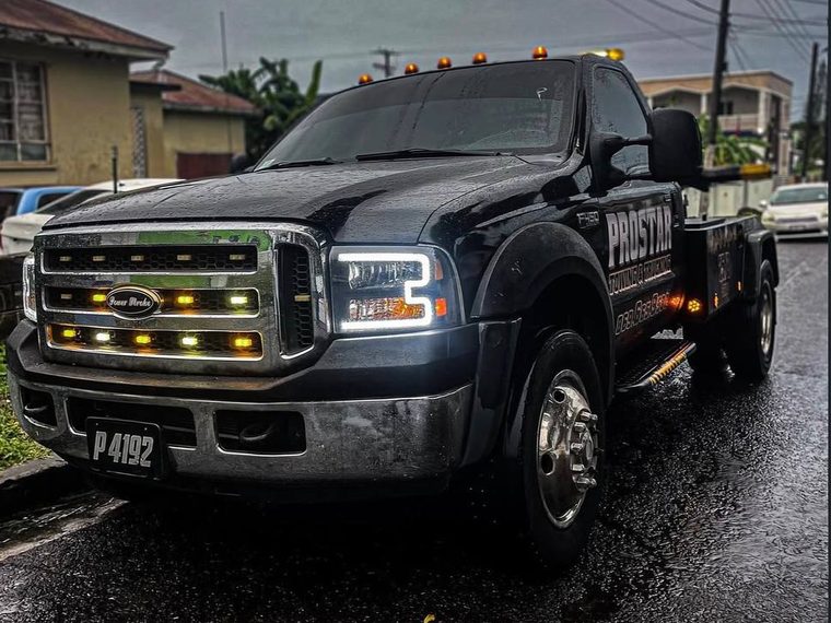 The black ProStar Ford Super Duty wrecker with its amber lights on